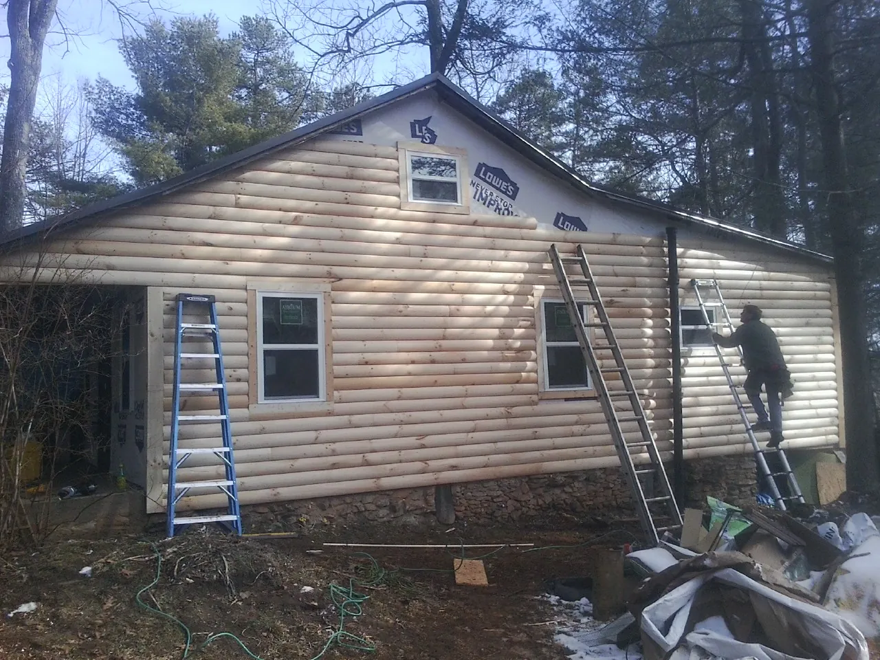 Ladders set against fresh log siding during an exterior remodel in Shattuck