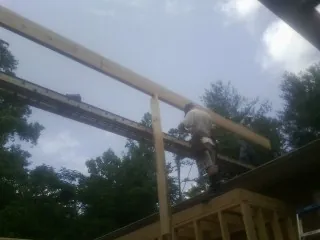 Carpenter setting a ridge beam over a new addition frame — Ice Dam Removal by Roofing Brothers in Shattuck