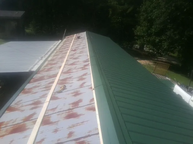 Old rusted panels beside newly installed green metal roofing — Wind Damage Roof Repair by Roofing Brothers in Shattuck
