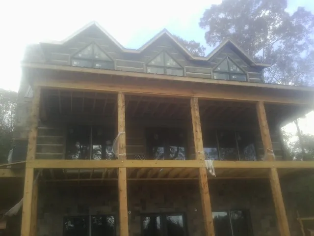 Dormers and porch framing on a large log home under construction — Roof Coating work by our crew in Shattuck