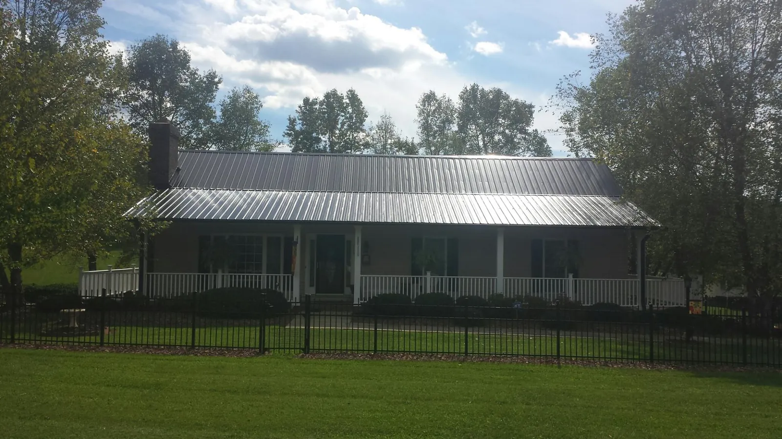 Gray metal roof on a brick ranch with a full width front porch — Gutter Guard Installation work by our crew in Shattuck