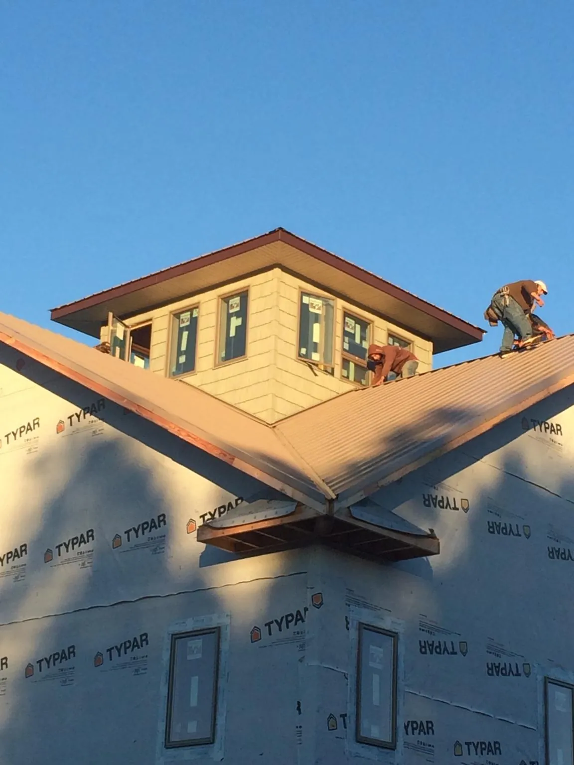 Roofers working around a rooftop cupola on a new metal roof at sunset — Roof Waterproofing in Shattuck by Roofing Brothers